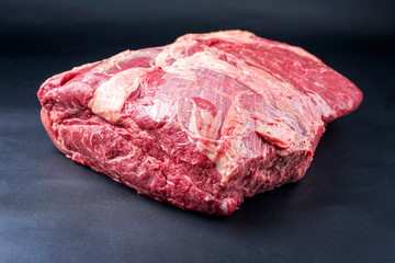 Raw dry aged wagyu beef shoulder clod roast as closeup on black background with copy space