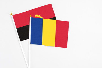 Romania and Angola stick flags on white background. High quality fabric, miniature national flag. Peaceful global concept.White floor for copy space.