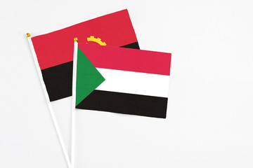 Sudan and Angola stick flags on white background. High quality fabric, miniature national flag. Peaceful global concept.White floor for copy space.