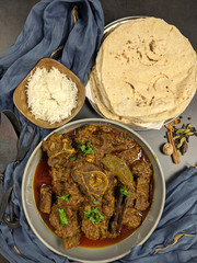 Overhead view of Goat curry, Mutton curry, Nihari, Rogan Josh in a bowl with Chapati and plain Rice.