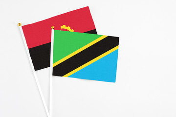Tanzania and Angola stick flags on white background. High quality fabric, miniature national flag. Peaceful global concept.White floor for copy space.