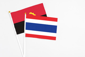 Thailand and Angola stick flags on white background. High quality fabric, miniature national flag. Peaceful global concept.White floor for copy space.