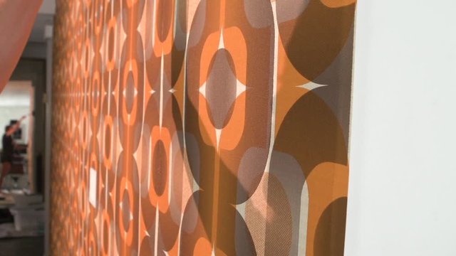 Real woman improving, renovating and decorating her home by hanging 1970's retro wallpaper