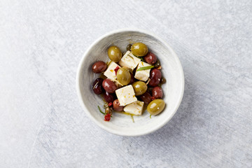 Green and Kalamata Olives, Capers and Feta Cheese on Bright Stone Background. Healthy Snack Idea. Top view. Copy space. 