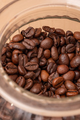 Freshly roasted coffee beans in a glass jar. On a stone background.
