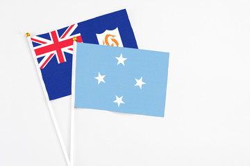Fototapeta premium Micronesia and Anguilla stick flags on white background. High quality fabric, miniature national flag. Peaceful global concept.White floor for copy space.