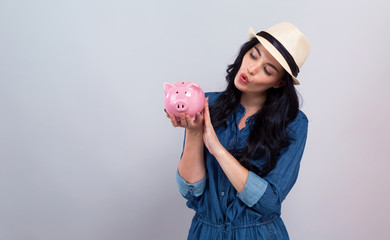 Young woman with a piggy bank on a gray background