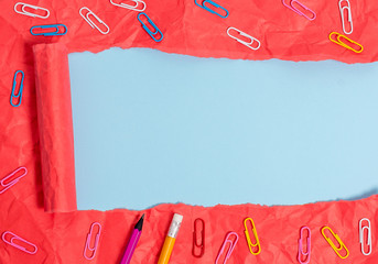Stationary and torn cardboard placed above a plain pastel table backdrop