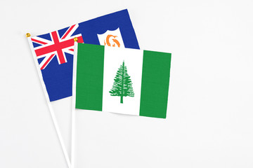 Norfolk Island and Anguilla stick flags on white background. High quality fabric, miniature national flag. Peaceful global concept.White floor for copy space.