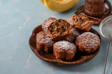 Banana muffins with oatmeal flakes sprinkled with icing sugar on a coconut plate, horizontal orientation