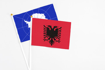Albania and Antarctica stick flags on white background. High quality fabric, miniature national flag. Peaceful global concept.White floor for copy space.