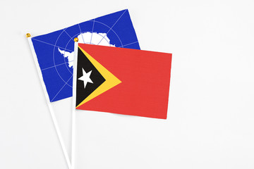 East Timor and Antarctica stick flags on white background. High quality fabric, miniature national flag. Peaceful global concept.White floor for copy space.
