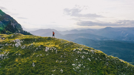 Naklejka premium Aerial view of a trail running man standing on the ridge of a mountain