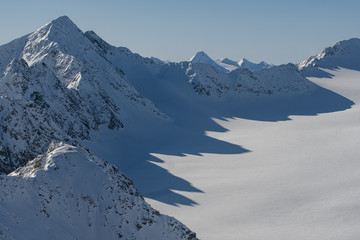 Mountain ridge cast shadow on a snowy fields