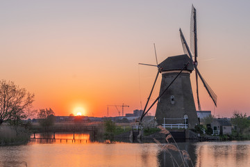Fototapeta na wymiar Golden red sunset cast on Windmills in Kinderdijk near Rotterdam, Netherlands