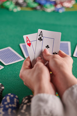 two aces in a player&rsquo;s hands on the background of a poker table and chips. casino, poker, a pair of aces