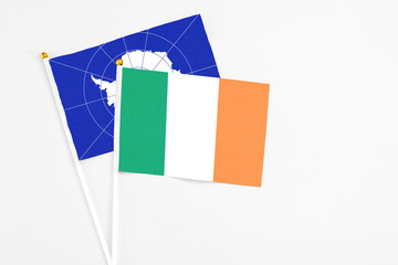 Ireland and Antarctica stick flags on white background. High quality fabric, miniature national flag. Peaceful global concept.White floor for copy space.