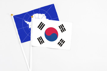 South Korea and Antarctica stick flags on white background. High quality fabric, miniature national flag. Peaceful global concept.White floor for copy space.