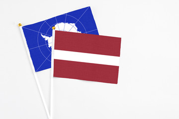 Latvia and Antarctica stick flags on white background. High quality fabric, miniature national flag. Peaceful global concept.White floor for copy space.