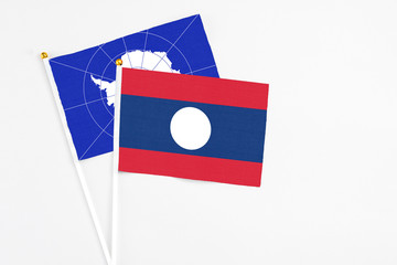 Laos and Antarctica stick flags on white background. High quality fabric, miniature national flag. Peaceful global concept.White floor for copy space.