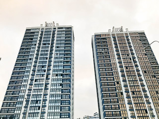 Obraz premium Tall beautiful monolithic-frame panel buildings, new buildings, skyscrapers, houses made of glass and concrete with many windows in the new district of the city. The background