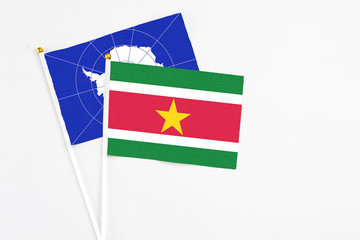 Suriname and Antarctica stick flags on white background. High quality fabric, miniature national flag. Peaceful global concept.White floor for copy space.