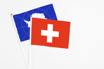 Switzerland and Antarctica stick flags on white background. High quality fabric, miniature national flag. Peaceful global concept.White floor for copy space.