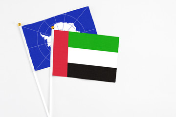 United Arab Emirates and Antarctica stick flags on white background. High quality fabric, miniature national flag. Peaceful global concept.White floor for copy space.
