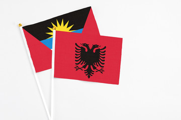 Albania and Antigua and Barbuda stick flags on white background. High quality fabric, miniature national flag. Peaceful global concept.White floor for copy space.