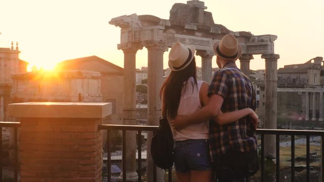 Young couple tourist looking at Roman Forum at sunrise hugging. Historical imperial Foro Romano in Rome, Italy from panoramic point of view.