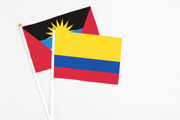Colombia and Antigua and Barbuda stick flags on white background. High quality fabric, miniature national flag. Peaceful global concept.White floor for copy space.