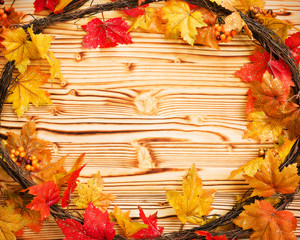 Autumn decoration in the form of circle of colored leafs on wooden background