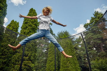Young Female Jumping On Trampoline Outdoors