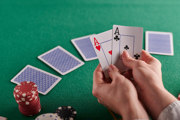 Poker, blackjack. Gaming business. Poker table with money, chips and a player holding a pair of aces. Internet poker, win