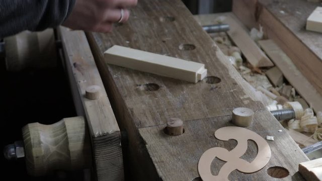 Male carpenter marking the wooden plank for the pine shelf with curved ruler and carpenters setsquare