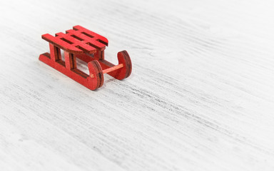 Miniature christmas sleigh on whfite wood as if sliding on snow
