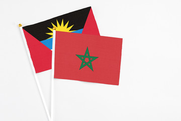 Morocco and Antigua and Barbuda stick flags on white background. High quality fabric, miniature national flag. Peaceful global concept.White floor for copy space.