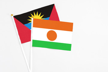 Niger and Antigua and Barbuda stick flags on white background. High quality fabric, miniature national flag. Peaceful global concept.White floor for copy space.