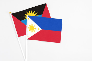 Philippines and Antigua and Barbuda stick flags on white background. High quality fabric, miniature national flag. Peaceful global concept.White floor for copy space.