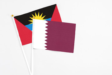 Obraz premium Qatar and Antigua and Barbuda stick flags on white background. High quality fabric, miniature national flag. Peaceful global concept.White floor for copy space.