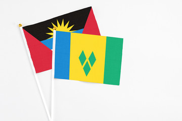 Saint Vincent And The Grenadines and Antigua and Barbuda stick flags on white background. High quality fabric, miniature national flag. Peaceful global concept.White floor for copy space.
