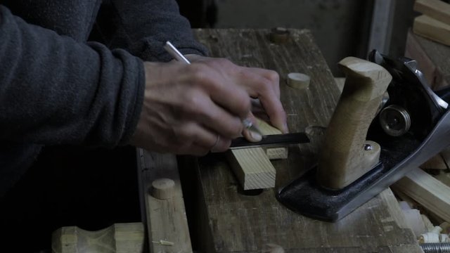 Male carpenter marking the wooden plank for the pine shelf with curved ruler and carpenters setsquare