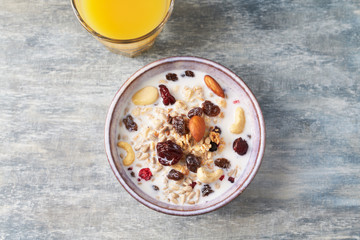 Bowl of granola with milk, nuts, raisins and cranberries. Concept for a tasty and healthy meal. Rustic wooden background. Top view. Close up. Copy space. 