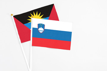 Slovenia and Antigua and Barbuda stick flags on white background. High quality fabric, miniature national flag. Peaceful global concept.White floor for copy space.