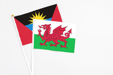 Wales and Antigua and Barbuda stick flags on white background. High quality fabric, miniature national flag. Peaceful global concept.White floor for copy space.