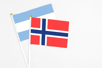 Obraz premium Bouvet Islands and Argentina stick flags on white background. High quality fabric, miniature national flag. Peaceful global concept.White floor for copy space.
