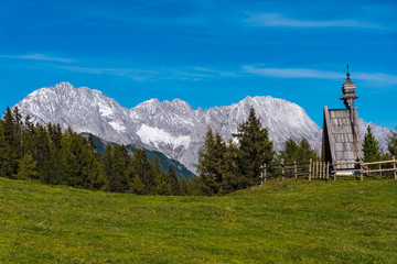 Fototapeta premium landscape in alps, meadow with wooden chapel in the wetterstein mountains, tyrol
