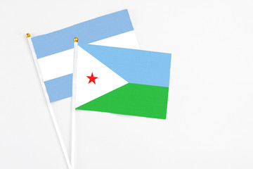 Djibouti and Argentina stick flags on white background. High quality fabric, miniature national flag. Peaceful global concept.White floor for copy space.