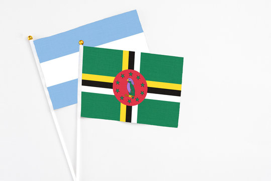 Dominica and Argentina stick flags on white background. High quality fabric, miniature national flag. Peaceful global concept.White floor for copy space.
