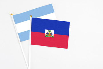 Haiti and Argentina stick flags on white background. High quality fabric, miniature national flag. Peaceful global concept.White floor for copy space.